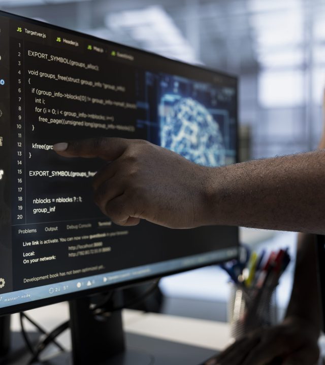System administrator using machine learning applications to optimize server farm operations. IT expert pointing to PC monitor, implementing server virtualization in data center facility